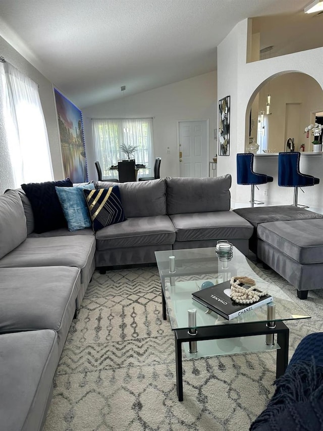 carpeted living room with a textured ceiling and vaulted ceiling