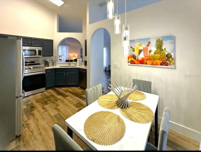 dining room featuring light hardwood / wood-style floors, a towering ceiling, and sink