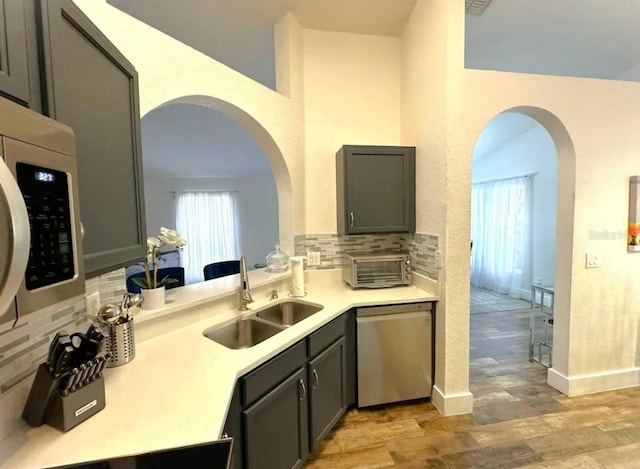 kitchen featuring tasteful backsplash, gray cabinetry, dishwasher, and sink