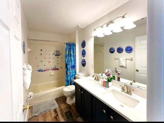 full bathroom with hardwood / wood-style floors, vanity, toilet, shower / bath combo with shower curtain, and a textured ceiling