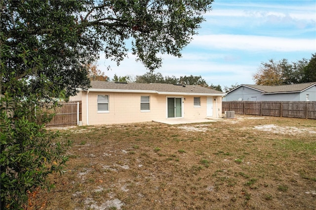 back of property with a patio area, a lawn, and central AC