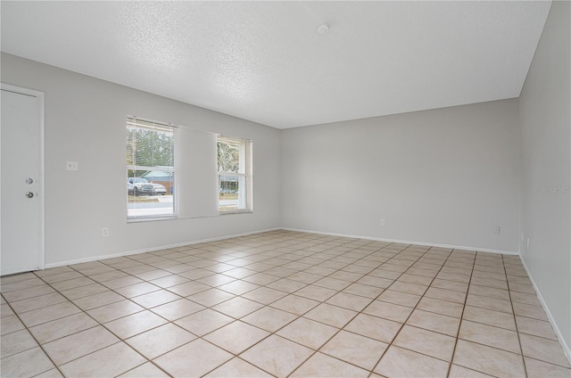 tiled empty room with a textured ceiling