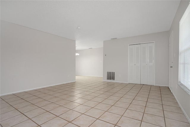 tiled empty room with a textured ceiling