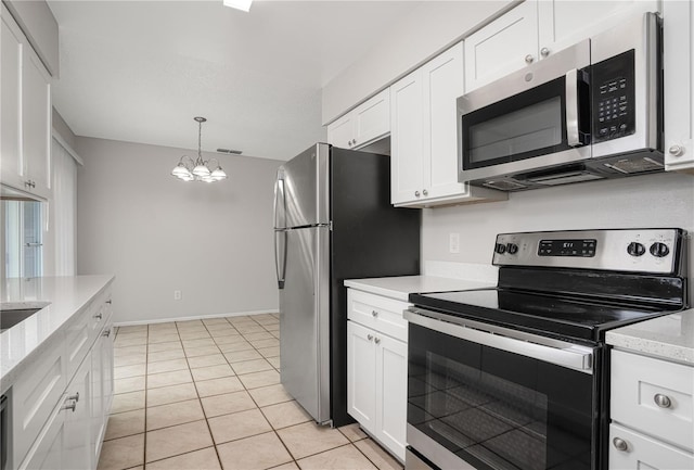 kitchen featuring light tile patterned floors, white cabinets, appliances with stainless steel finishes, and a notable chandelier