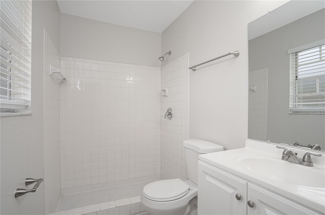 bathroom with toilet, vanity, and tiled shower