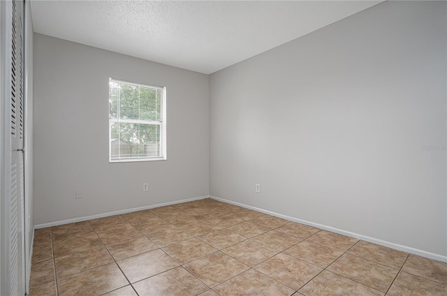 tiled spare room featuring a textured ceiling