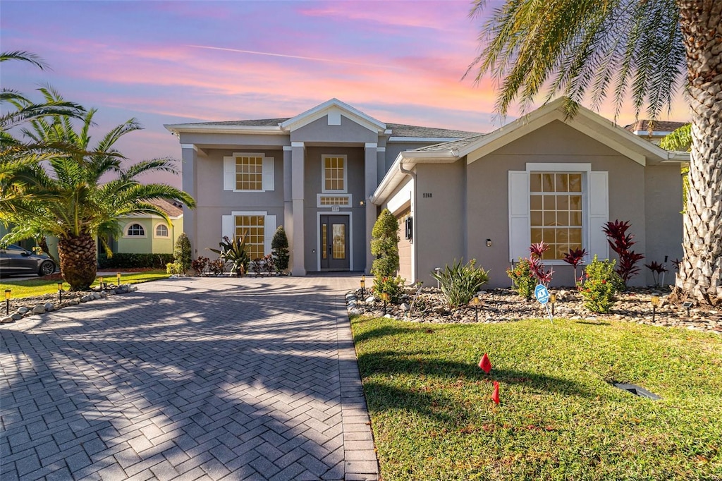 view of front of home featuring decorative driveway, a front yard, and stucco siding