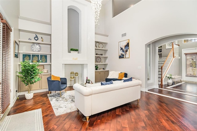 living room featuring dark hardwood / wood-style flooring, built in features, and a high ceiling