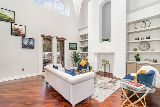 living room with built in features, dark wood-type flooring, and a towering ceiling