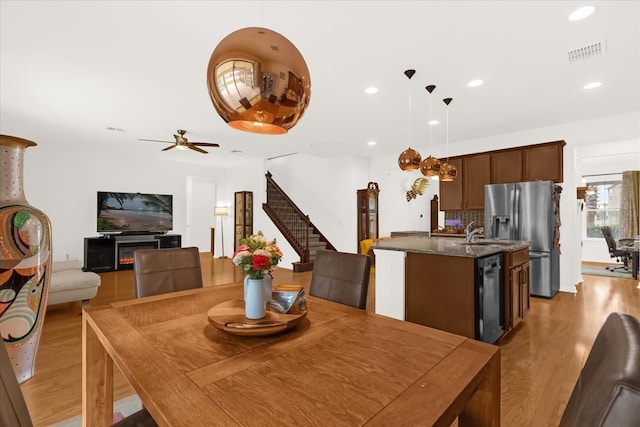 dining space with ceiling fan, sink, and light hardwood / wood-style floors