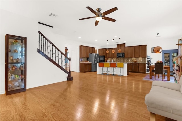 living room with light hardwood / wood-style floors and ceiling fan