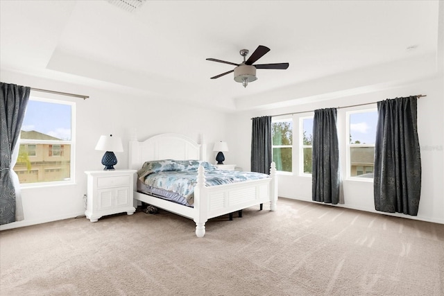 carpeted bedroom featuring ceiling fan and a raised ceiling