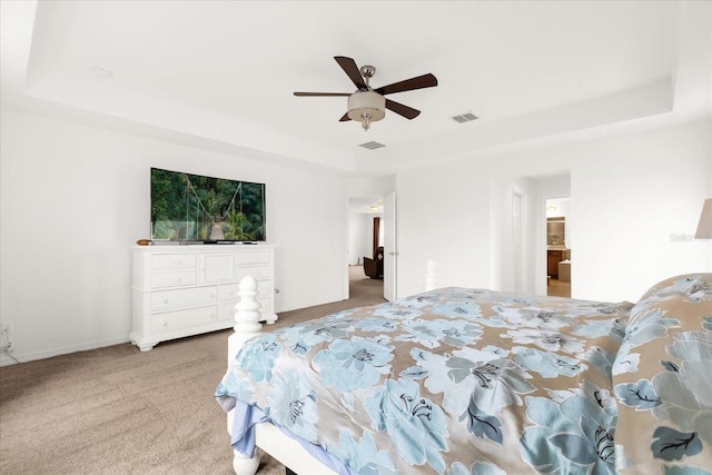 bedroom with carpet flooring, ceiling fan, a raised ceiling, and ensuite bathroom