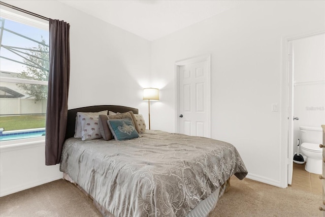 bedroom with connected bathroom, multiple windows, and light carpet