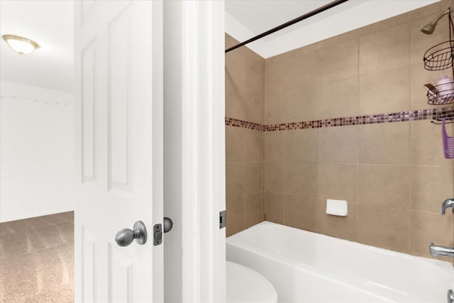 bathroom with tiled shower / bath combo and toilet