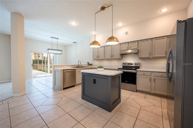 kitchen featuring gray cabinetry, kitchen peninsula, pendant lighting, a kitchen island, and appliances with stainless steel finishes