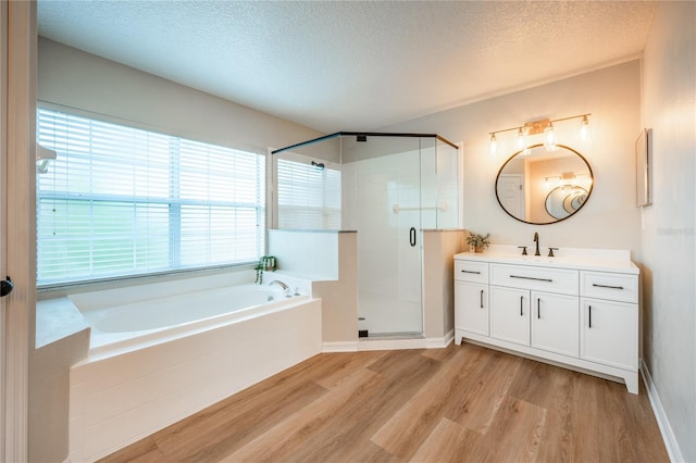 bathroom featuring plus walk in shower, vanity, a textured ceiling, and hardwood / wood-style flooring