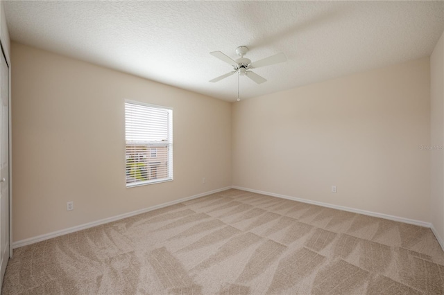 carpeted spare room with a textured ceiling and ceiling fan