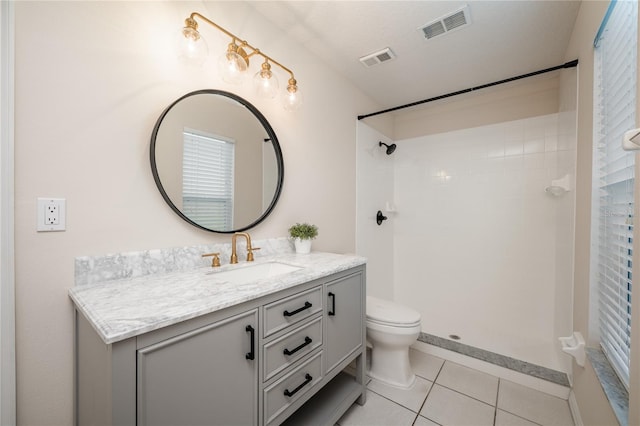 bathroom featuring tile patterned flooring, vanity, toilet, and a shower