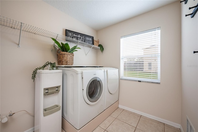 laundry area with washing machine and dryer, light tile patterned floors, and a textured ceiling