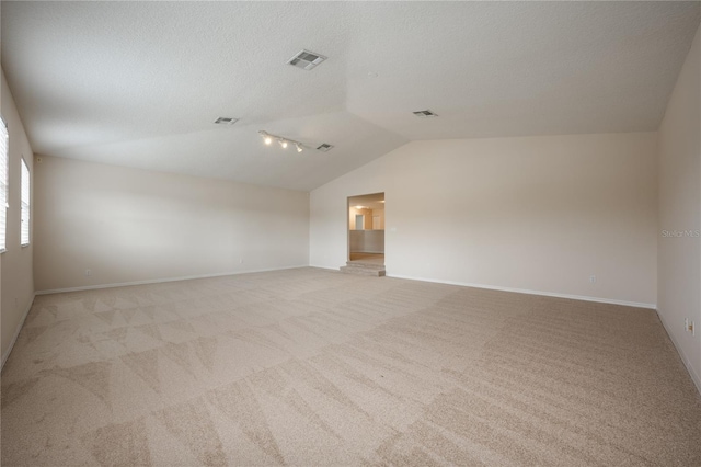 carpeted empty room with lofted ceiling and a textured ceiling