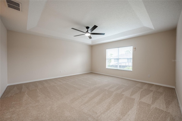 spare room featuring a textured ceiling, a raised ceiling, and ceiling fan