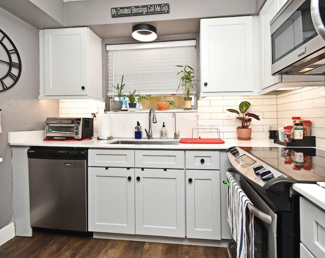 kitchen featuring decorative backsplash, appliances with stainless steel finishes, sink, dark hardwood / wood-style floors, and white cabinetry