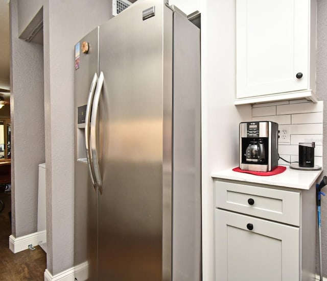 kitchen featuring stainless steel fridge, dark hardwood / wood-style flooring, tasteful backsplash, and white cabinetry