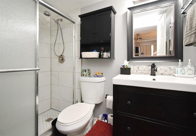 bathroom featuring ceiling fan, backsplash, toilet, a shower with door, and vanity