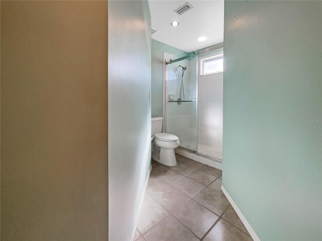 bathroom featuring toilet, tile patterned floors, and a shower with shower door