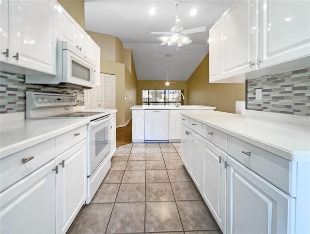 kitchen featuring lofted ceiling, white appliances, white cabinets, decorative backsplash, and light tile patterned floors