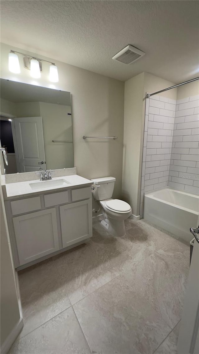 full bathroom with tile patterned floors, a textured ceiling, toilet, vanity, and tiled shower / bath