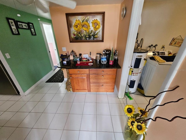 interior space with washer / dryer, light tile patterned floors, and water heater