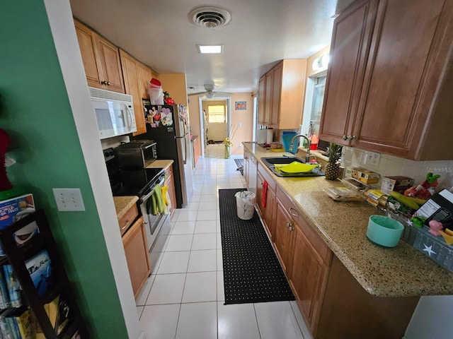 kitchen with light stone counters, sink, light tile patterned floors, and stainless steel appliances