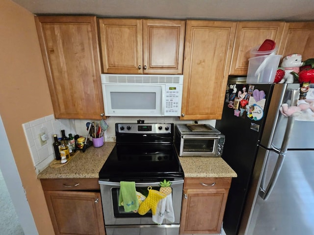 kitchen featuring stainless steel appliances, light stone counters, and tasteful backsplash