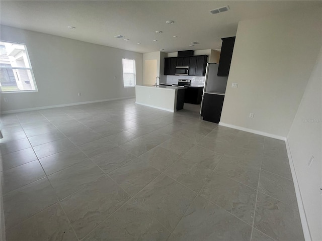 unfurnished living room with a healthy amount of sunlight, sink, and light tile patterned floors