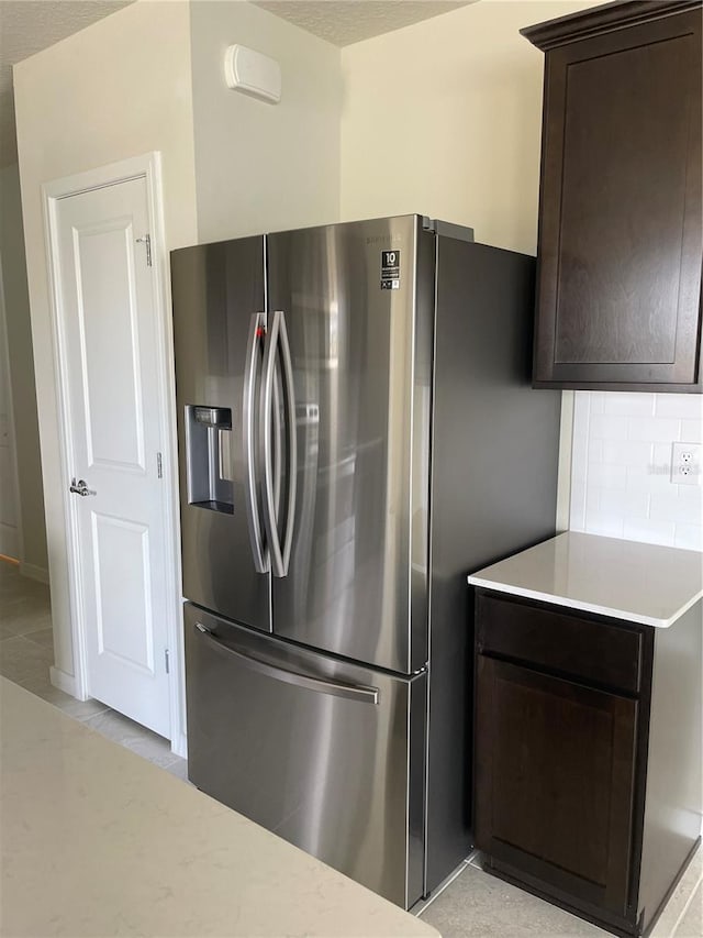 kitchen featuring stainless steel refrigerator with ice dispenser, decorative backsplash, and dark brown cabinetry