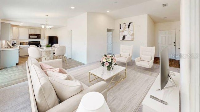 living room with light hardwood / wood-style floors and a notable chandelier