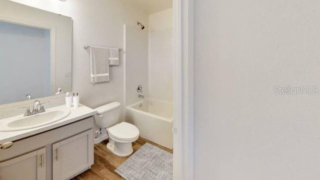 full bathroom with washtub / shower combination, vanity, hardwood / wood-style flooring, and toilet