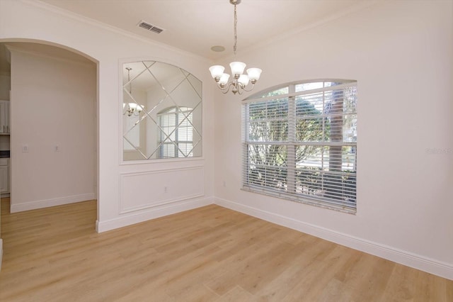 unfurnished dining area featuring a notable chandelier, ornamental molding, and light wood-type flooring