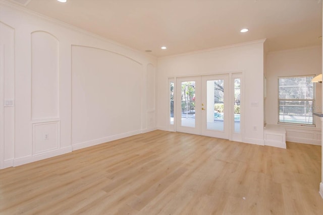 unfurnished room with crown molding, a wealth of natural light, light hardwood / wood-style floors, and french doors