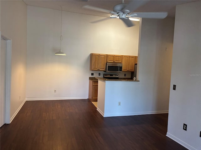 kitchen with range, ceiling fan, dark wood-type flooring, decorative light fixtures, and a high ceiling