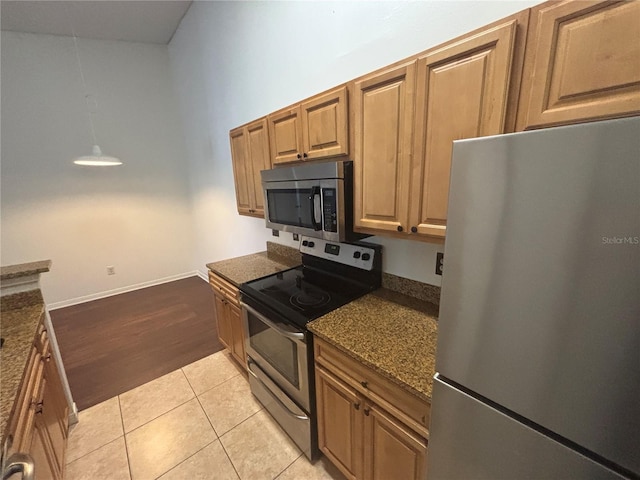 kitchen with light tile patterned floors, appliances with stainless steel finishes, and dark stone counters