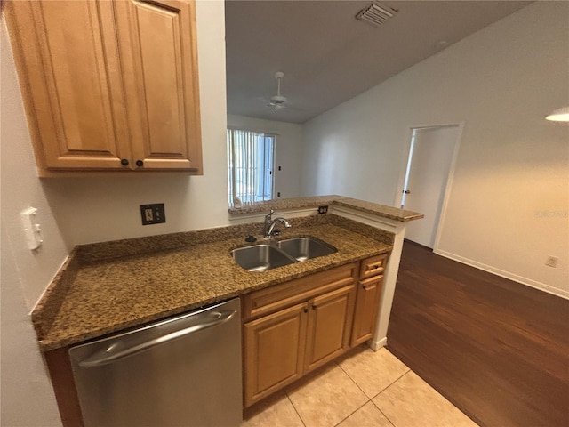 kitchen featuring kitchen peninsula, stainless steel dishwasher, sink, light tile patterned floors, and dark stone countertops