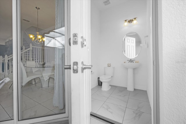 bathroom featuring sink, a chandelier, and toilet