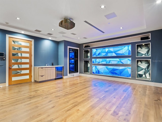 workout area with built in shelves, light hardwood / wood-style floors, and bar