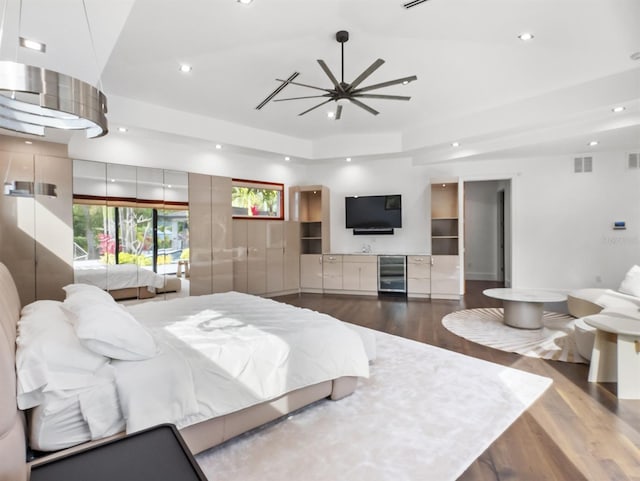 bedroom featuring dark wood-type flooring, beverage cooler, and a tray ceiling