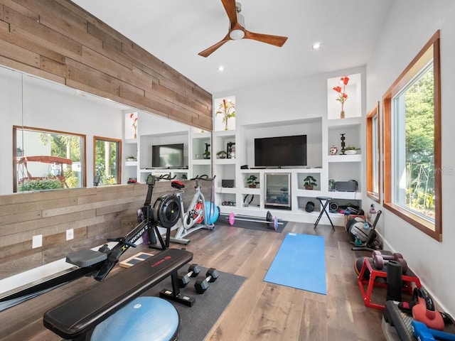 workout area featuring wooden walls, built in features, ceiling fan, and hardwood / wood-style flooring