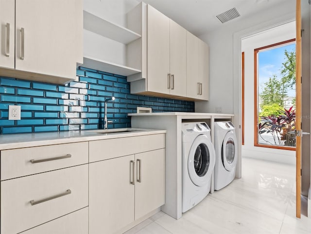 clothes washing area with cabinets, separate washer and dryer, and sink