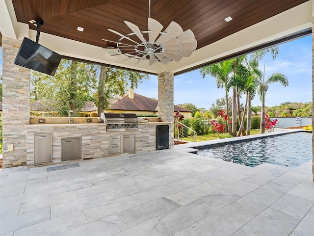 view of pool featuring an outdoor kitchen, ceiling fan, area for grilling, and a patio